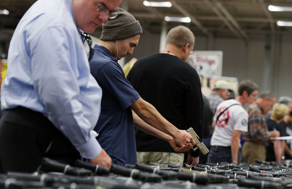 Potential buyers try out guns which are displayed on an exhibitor's table during the Nation's Gun Show on November 18, 2016 at Dulles Expo Center in Chantilly, Virginia. Alex Wong/Getty Images/AFP