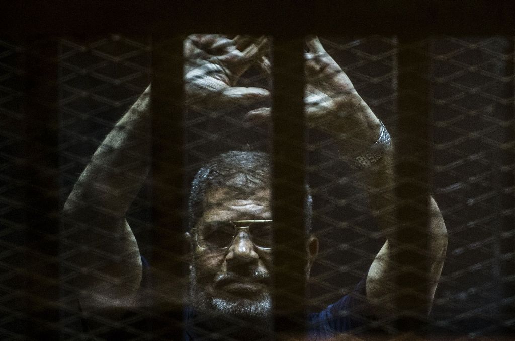 A file picture taken on June 2, 2015 shows ousted Egyptian president Mohamed Morsi gesturing from the defendants cage as he attends his trial at the police academy on the outskirts of the capital Cairo. / AFP.