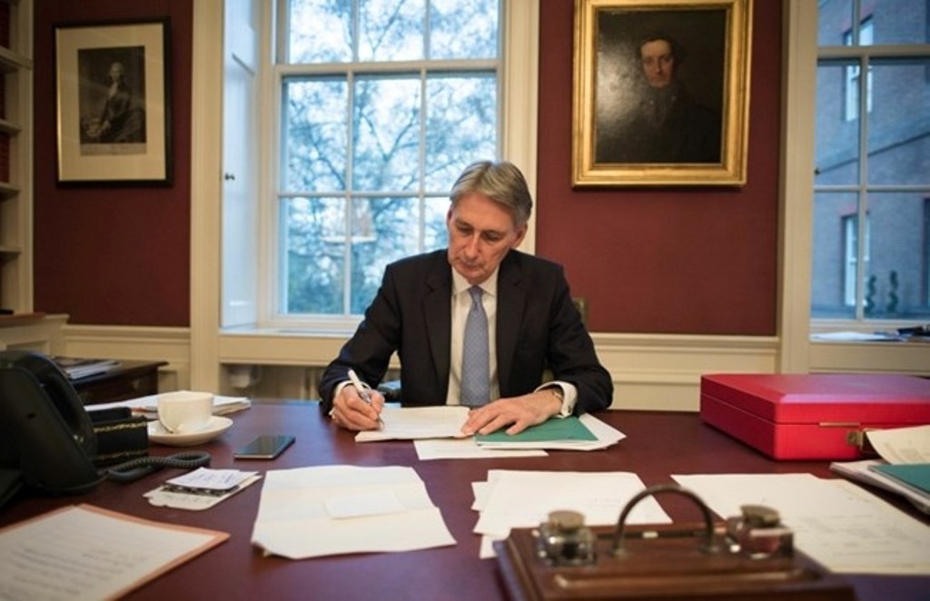 British Chancellor of the Exchequer Philip Hammond is pictured sitting at his desk, with a copy of his Autumn Statement, in his office at 11 Downing Street in central London on Nov. 22, 2016. / AFP / POOL / Stefan Rousseau