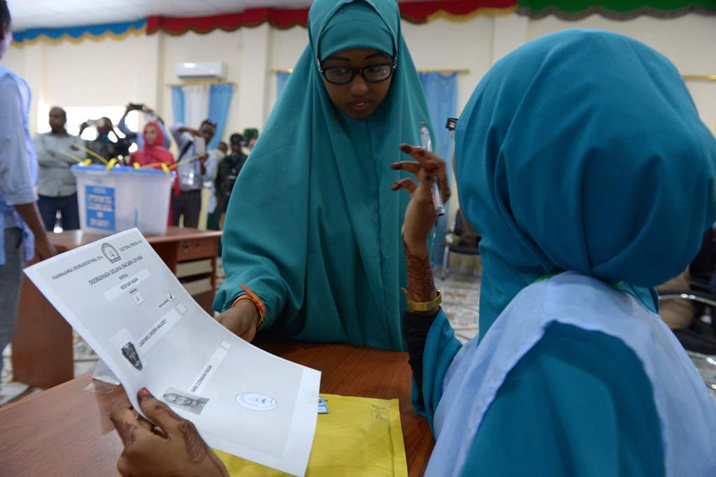 (FILES) This file photo taken on November 16, 2016 shows a Somali polling agent (R) explaining the voting procedure to a voter before she casts her ballot in Baidoa. AFP / SIMON MAINA