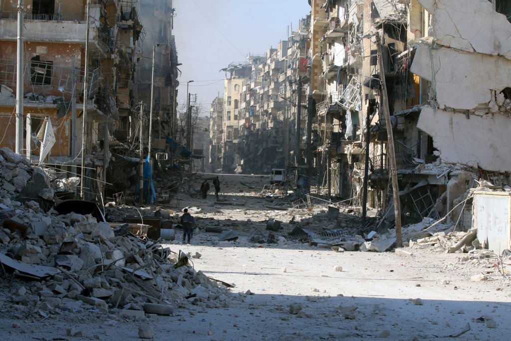 Syrians walk over rubble of damaged buildings, while carrying their belongings, as they flee clashes between government forces and rebels in Tariq al-Bab and al-Sakhour neighborhoods of eastern Aleppo towards other rebel held besieged areas of Aleppo, Syr