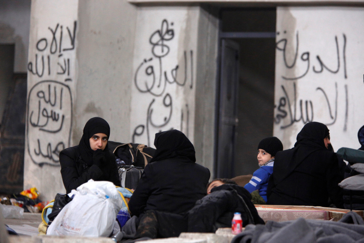 Syrians evacuated from eastern Aleppo, rest inside a shelter in government controlled Jibreen area in Aleppo, Syria December 1, 2016. Writings on the wall read in Arabic, 
