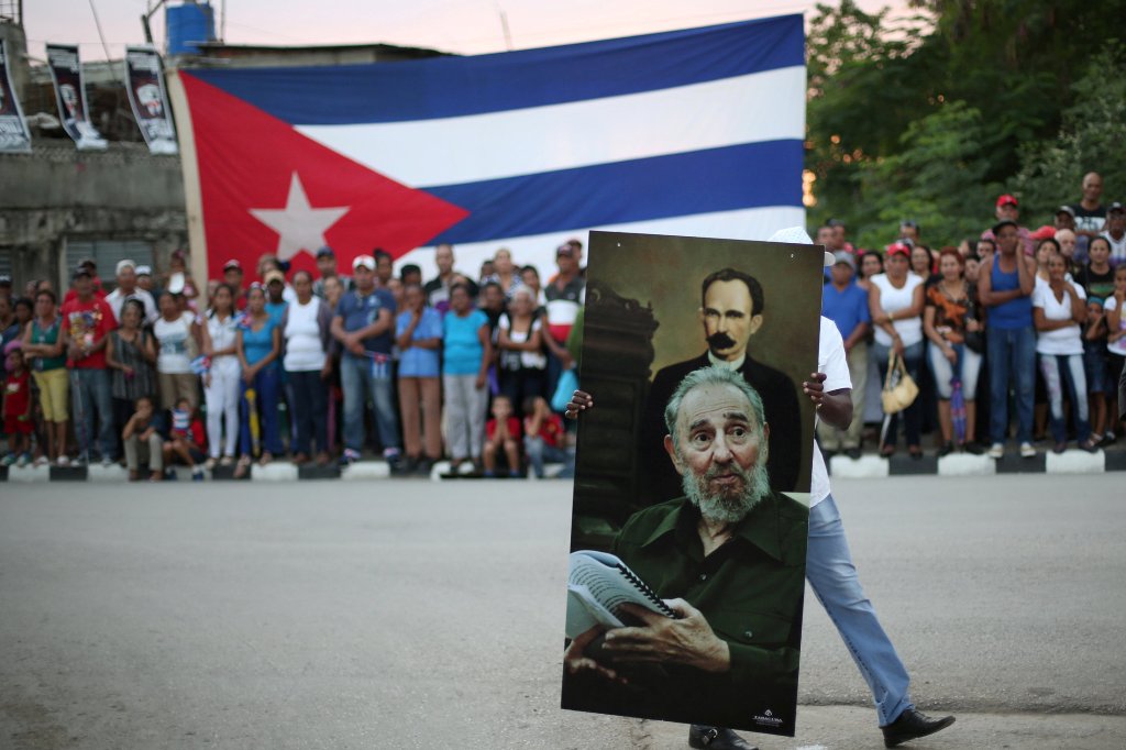 A man carries a picture showing Cuba's former President Fidel Castro and Jose Marti, the 19th century hero of Cuban independance, as people line the street while waiting for the ashes of Castro to pass during a journey to the eastern city of Santiago de C