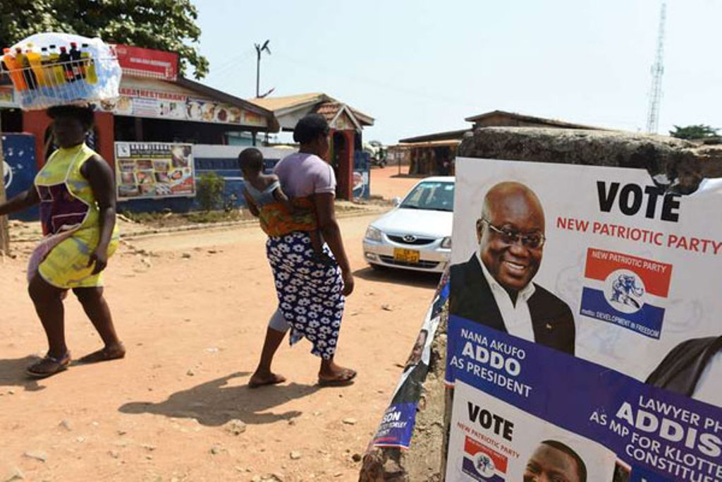 People walk past a campaign poster of Presidential candidate of the opposition New Patriotic Party (NPP) Nana Akufo-Addo in Accra, on December 3, 2016 ahead of the December 7 election. PHOTO | PIUS UTOMI EKPEI | AFP.