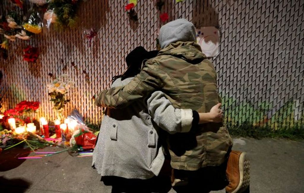 Rachel Saxer (L) embraces friend La Tron at a makeshift memorial near the scene of a fatal warehouse fire in the Fruitvale district of Oakland, California, U.S. December 4, 2016. / STEPHEN LAM / REUTERS.