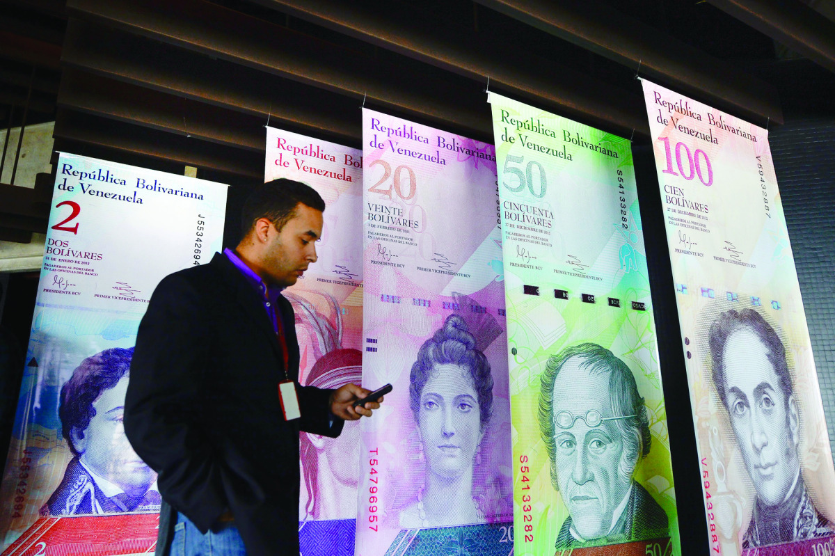 A man walks past banners showing Venezuela's currency, the bolivar, at the Central Bank of Venezuela (BCV) in Caracas. The BCV presented the new bank notes that will be in circulation from December 15, 2016, including a 20,000 bolivars bill.