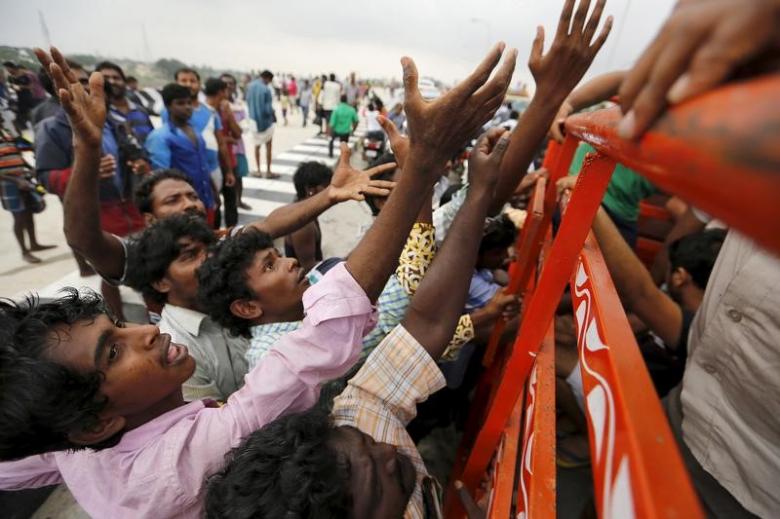 Displaced residents raise their hands to receive free food distributed by volunteers in the flood-affected areas of Chennai, India, December 3, 2015. REUTERS/Anindito Mukherjee