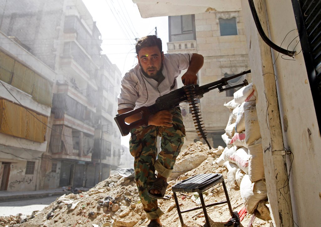 A Free Syrian Army fighter takes cover during clashes with Syrian Army in the Salaheddine neighbourhood of central Aleppo August 7, 2012. REUTERS/Goran Tomasevic/File Photo
