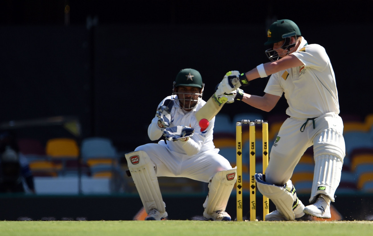 Australia's batsman Steven Smith plays a shot as Pakistan's wicketkeeper Sarfraz Ahmed looks on during the first day-night cricket Test between Australia and Pakistan at Gabba stadium in Brisbane on December 15, 2016. (AFP / SAEED KHAN)
