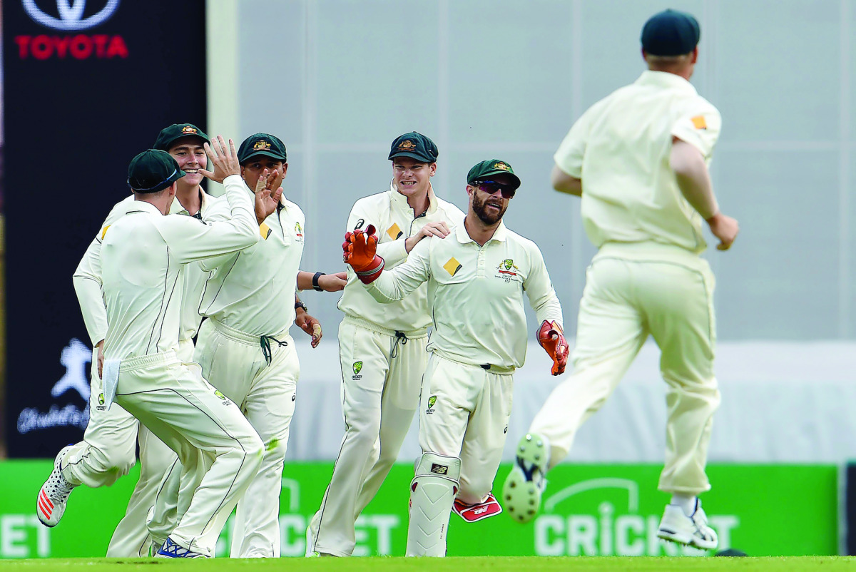 Australia's team players celebrate the dismissal of Pakistan's batsman Azhar Ali during the second day of the day-night Test match at the Gabba in Brisbane, yesterday.