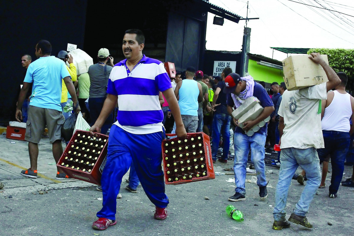 People carry goods taken from a food wholesaler after it was broken into, in La Fria, Venezuela, yesterday.