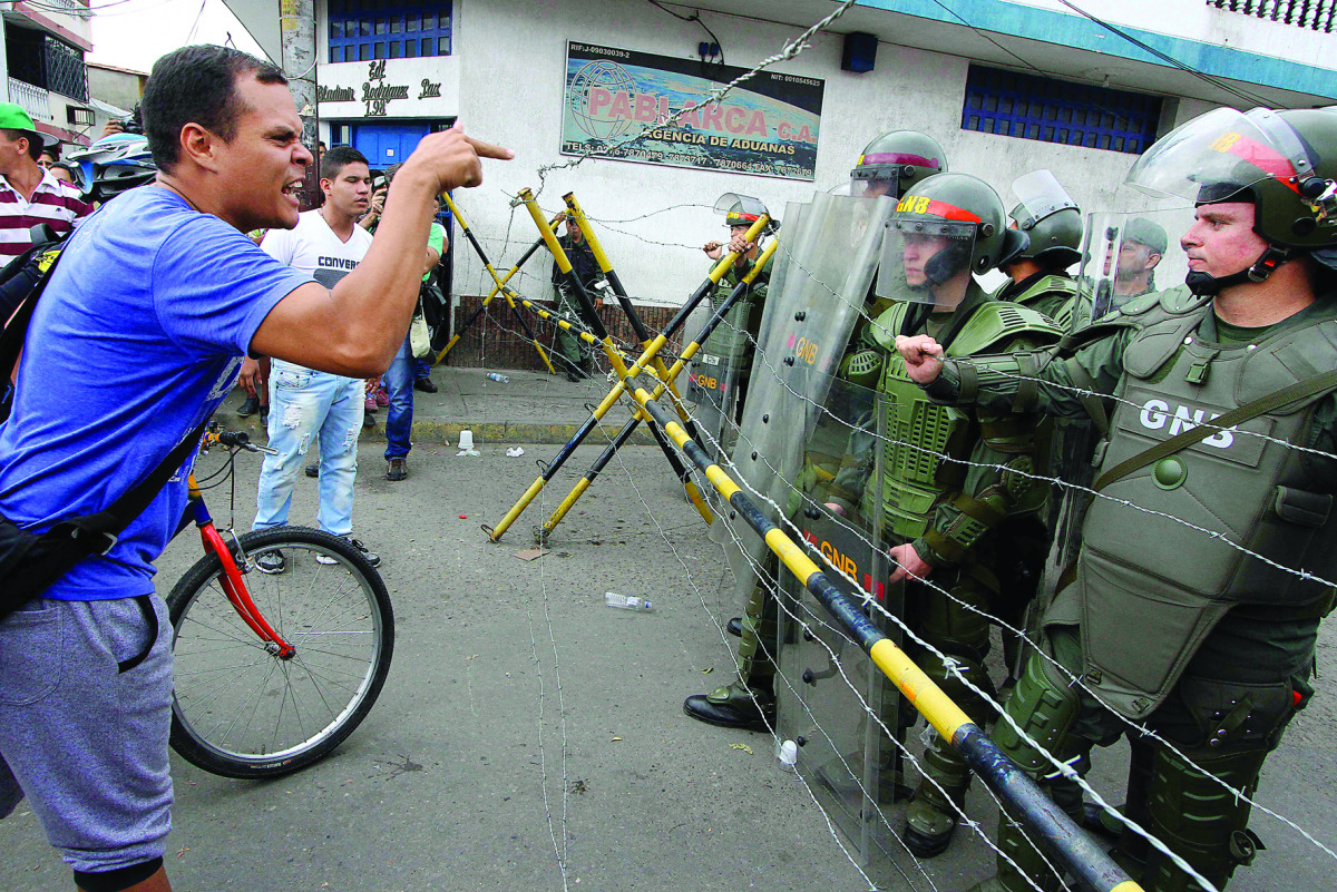 People confront Bolivarian National Guard member while attempting to cross the Francisco de Paula Santander international bridge, linking Urena, in Venezuela and Cucuta, in Colombia, despite the border closing order issued by the Venezuelan government.
