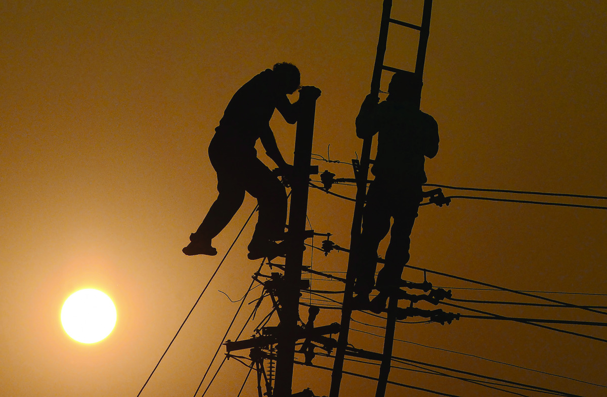 Workers adjust electricity cables set up temporarily on the banks of the River Ganges in Allahabad on December 19, 2016, in preparation for the annual Hindu religious fair of Magh Mela. The Magh Mela is held every year on the banks of Triveni Sangam - the
