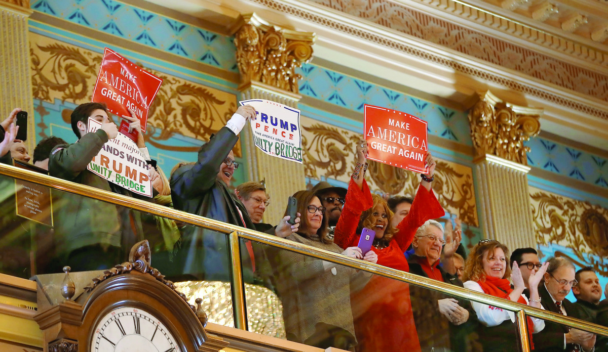 Supporters of President-elect Donald Trump hold signs in the Senate gallery in Lansing, Michigan.