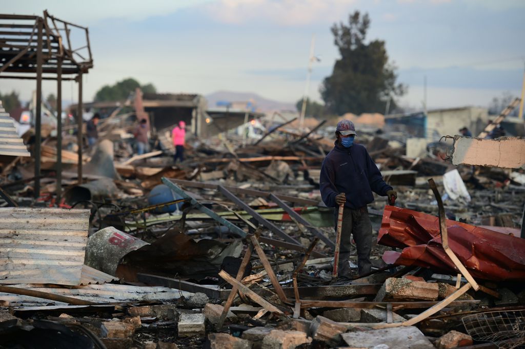 Firefighters work amid the debris left by a huge blast that occured in a fireworks market in Mexico City, on December 20, 2016 killing at least nine people and injuring 70, according to police. The conflagration, in the suburb of Tultepec, set off a quick