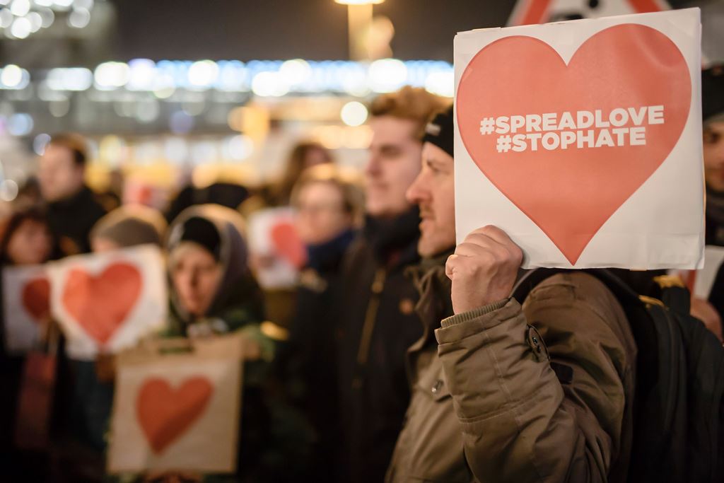 A protester holds a sign with a red heart reading the hashtags 'spreadlove' and 'stophate' during an anti right wing demonstration near the place of the terror attack on a Christmas market in Berlin on December 21, 2016. AFP / CLEMENS BILAN