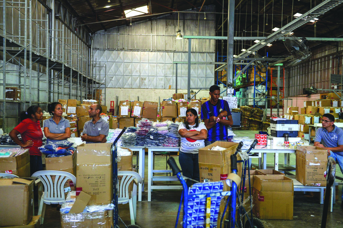 Employees wait during an inspection by the National Superintendency of Costs and Prices in a warehouse in Caracas on December 21, 2016. The National Superintendency of Costs and Prices intervened in the clothing company EPK to order it to immediately cut 