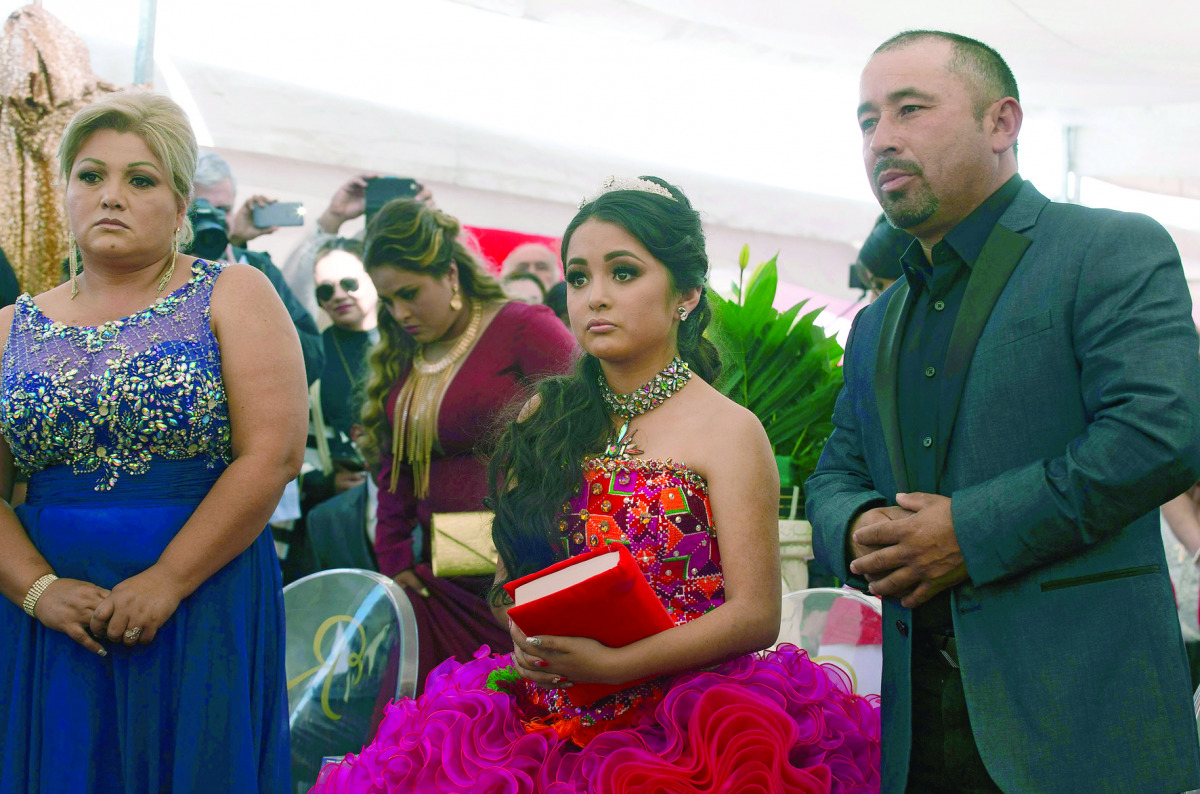 Rubi Ibarra is pictured between her parents Cresencio (right) and Anaelda during a mass for her 15th birthday celebrations in La Joya, San Luis Potosi State. 