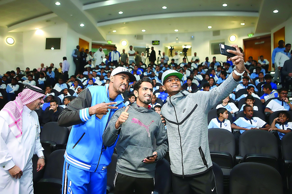 Yasseen Ismail, Mohammed Saadon al Kuwari and Mutaz Barshimtake take a selfie with student-athletes following a panel discussion at the Aspire Academy.