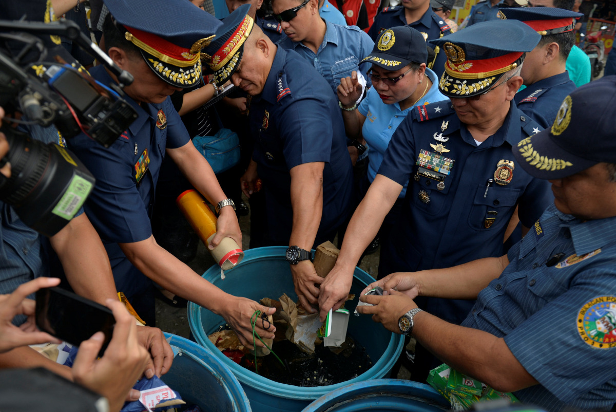 Philippine National Police (PNP) Director General Ronald Dela Rosa (C), along with other police officials, dunks confiscated illegal firecrackers into a tub of water to render them unusable, during an inspection of firecracker shops ahead of new year cele