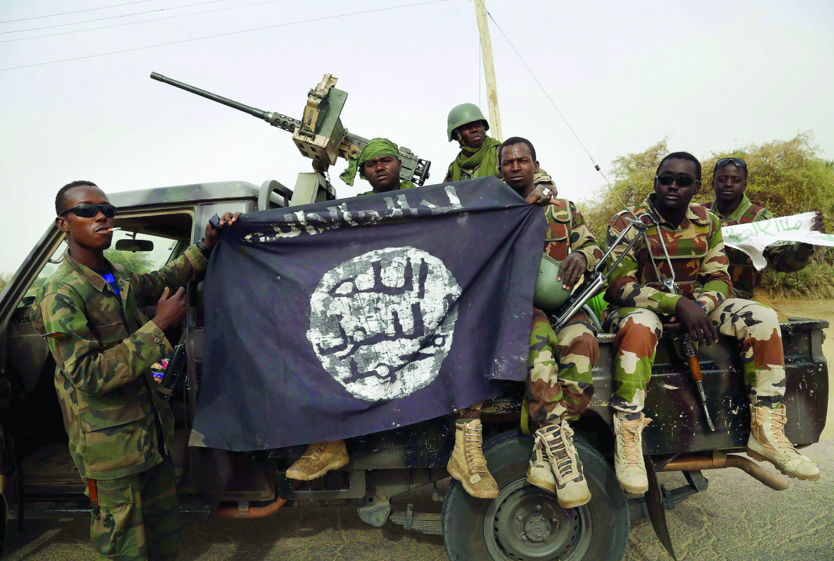 Nigerien soldiers hold up a Boko Haram flag they seized in the recently retaken town of Damasak, Nigeria.