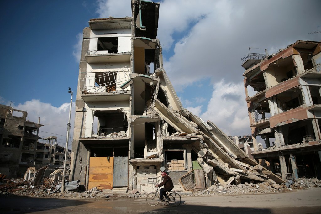 A man rides a bicycle near damaged buildings in the rebel held besieged city of Douma, in the eastern Damascus suburb of Ghouta, Syria December 30, 2016. REUTERS/Bassam Khabieh TPX IMAGES OF THE DAY.