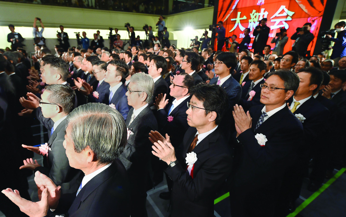 Business leaders and investors clap their hands during the closing ceremony to celebrate the last trading day of 2016 at the Tokyo Stock Exchange in Tokyo on December 30, 2016. Tokyo's benchmark stock index ended a volatile 2016 to mark the fifth annual g
