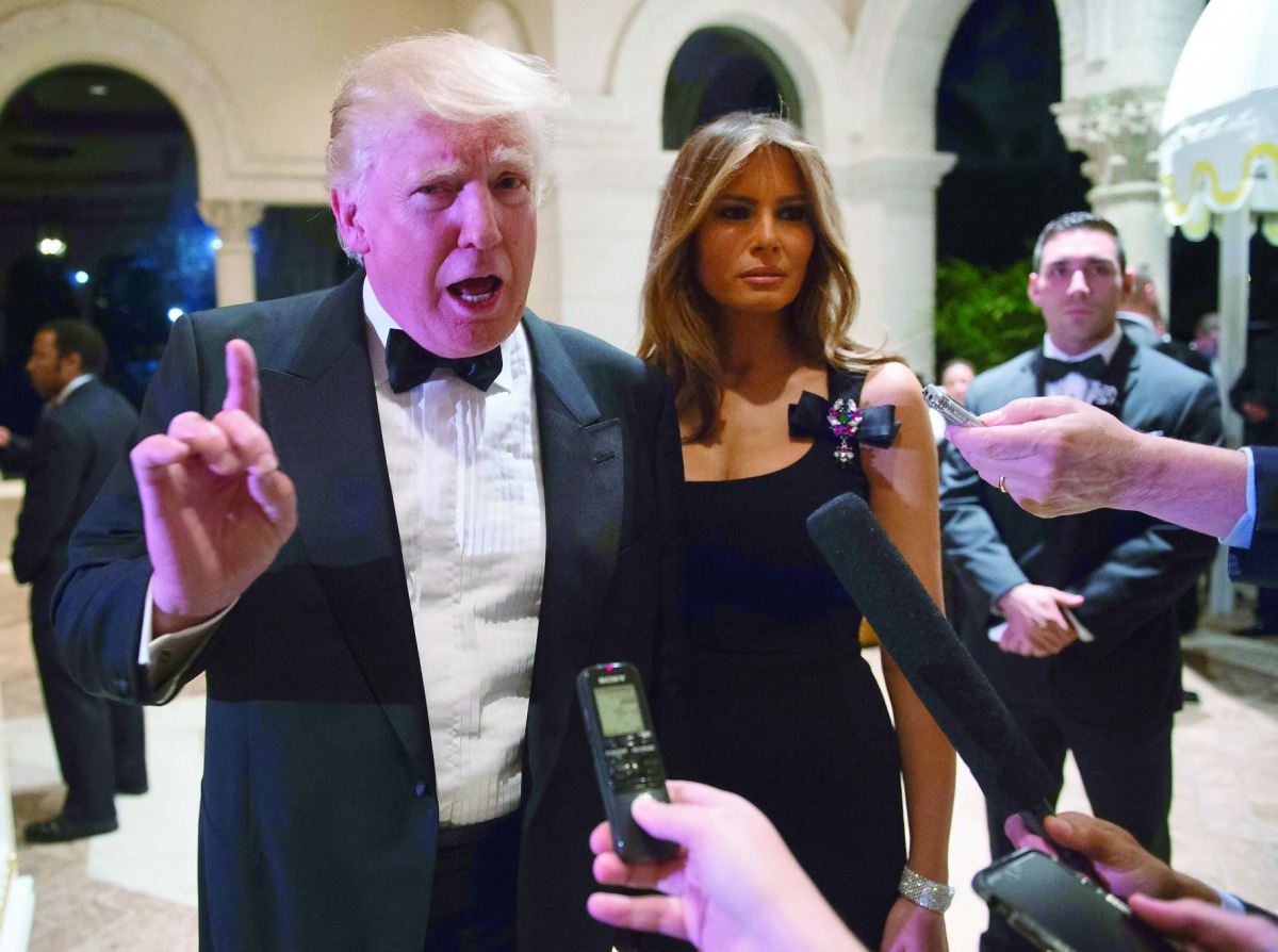 US President-elect Donald Trump, accompanied by wife Melania, answers questions from reporters at a New Year party at Mar-a-Lago in Palm Beach.
