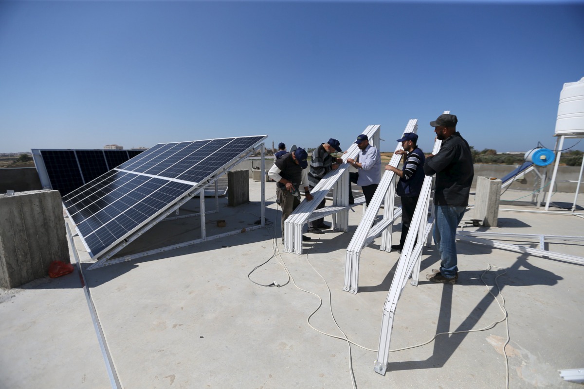 Palestinian workers install solar panels atop the roof of a medical centre in Gaza City, March 1, 2016 (REUTERS / Ibraheem Abu Mustafa) 