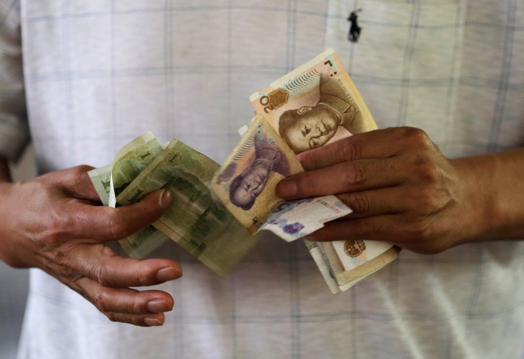  A customer counts Chinese Yuan notes at a market in Beijing, August 12, 2015. REUTERS/Jason Lee/File Photo