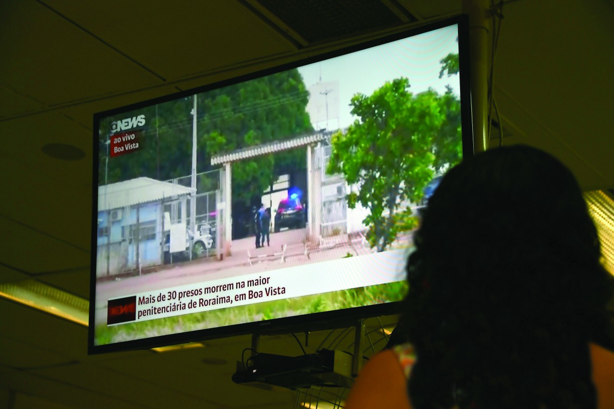 A woman watches on television news about the riot in the PAMC (Agricola de Monte Cristo Penitentiary) in Roraima, northern Brazil, yesterday.