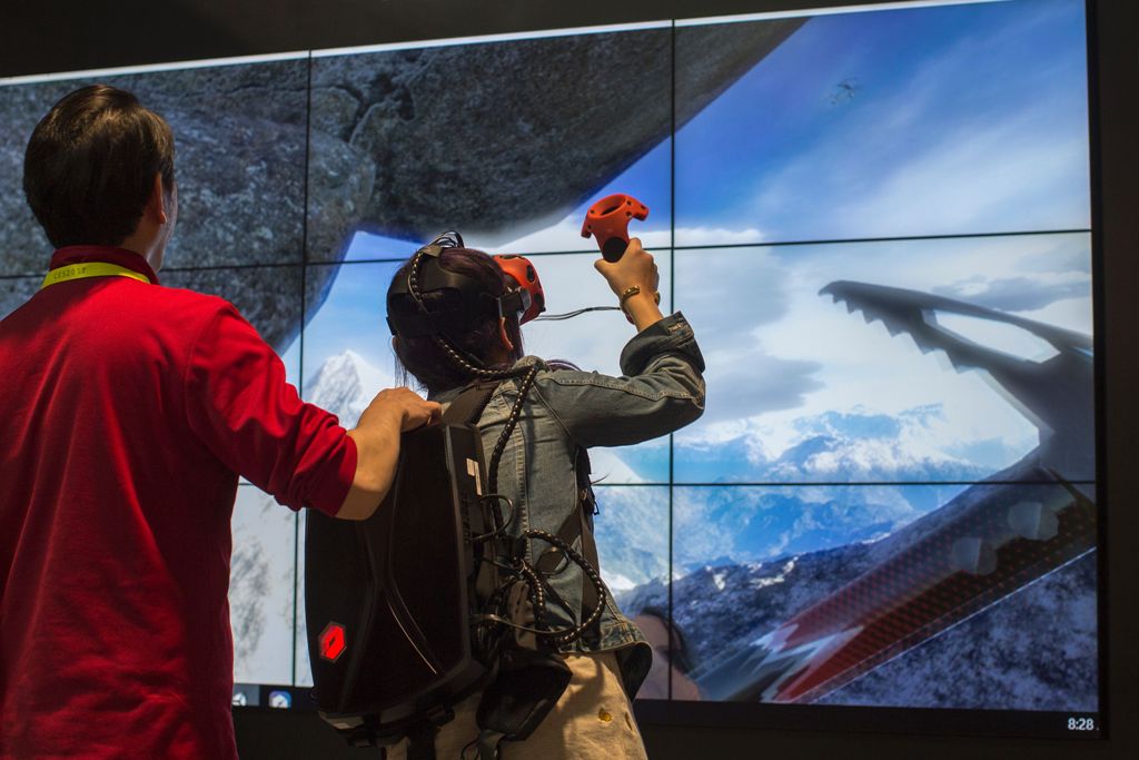 A woman climbs a mountain in a VR experience at the Tsinghua Tongfang exhibit booth during the 2017 Consumer Electronic Show (CES) in Las Vegas, Nevada, January 6, 2017. / AFP / DAVID MCNEW
