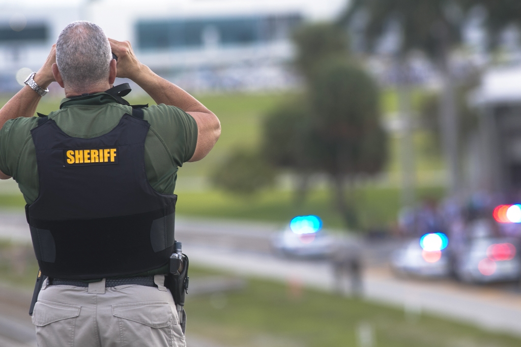 A Broward County sheriff’s deputy stands on a highway entering Fort Lauderdale International Airport, using binoculars to look towards the airport on January 06, 2017 in Florida, USA. ( Carlos Miller - Anadolu Agency )
