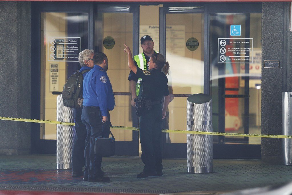 Airport security personnel stand in front of one of the entrances to the baggage area of Terminal 2, where yesterday a shooter killed five people and wounded six others before he was taken into custody, at the Fort Lauderdale-Hollywood International airpo
