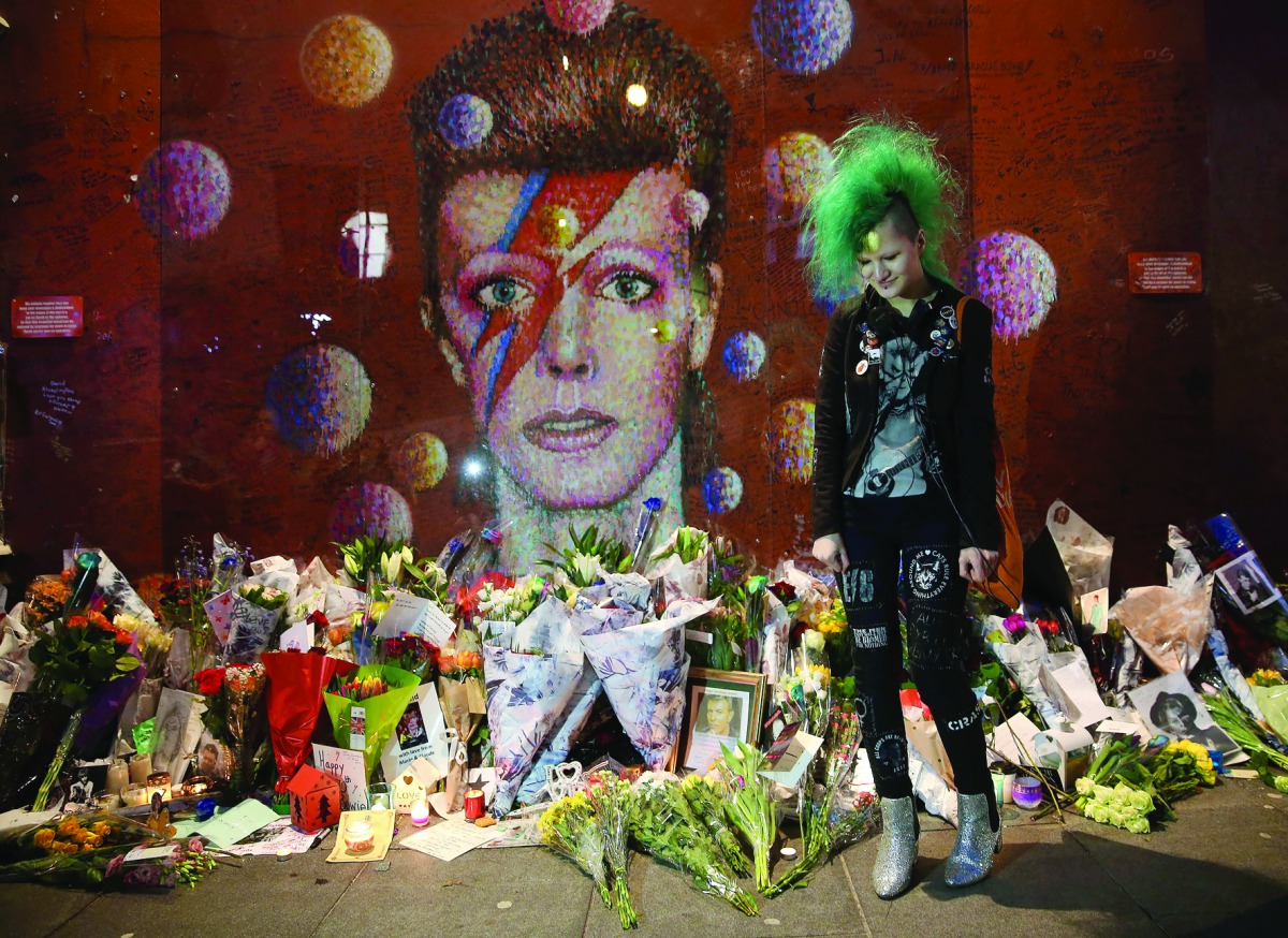 A fan poses in front of the mural of late British pop icon David Bowie on the first anniversary of Bowie's death, yesterday.