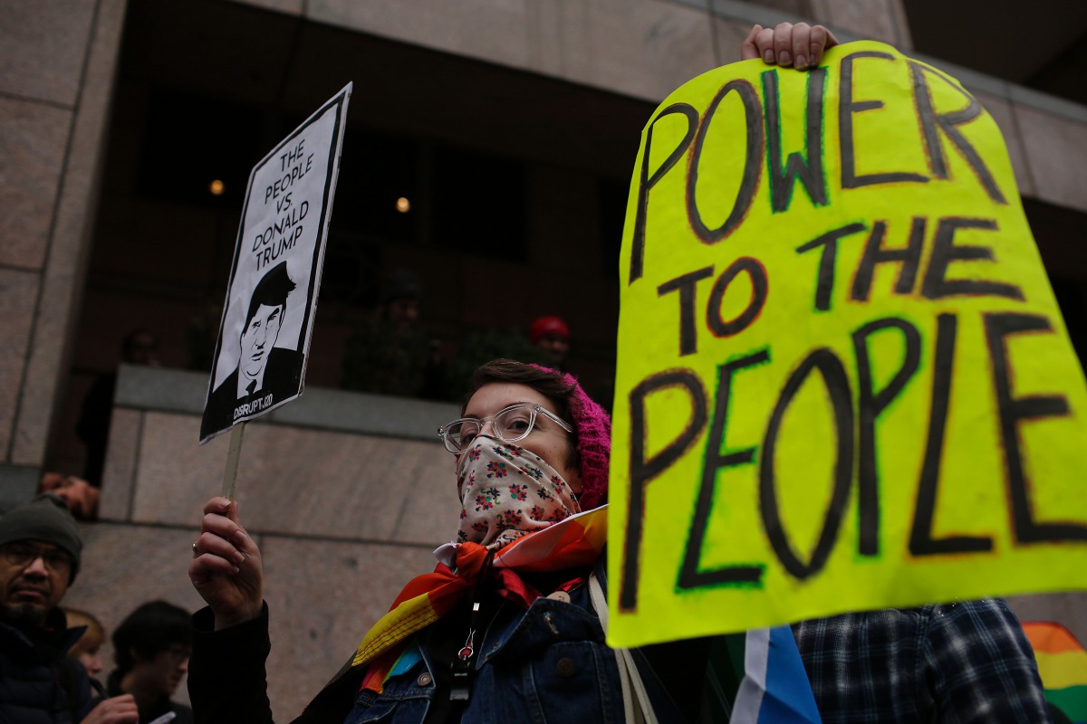 A woman protesting the inauguration of Donald Trump holds signs before the start of the Presidential Inauguration of Trump near Freedom Plaza on January 20, 2017 in Washington, DC. Trump will become the 45th President of the United States after a swearing