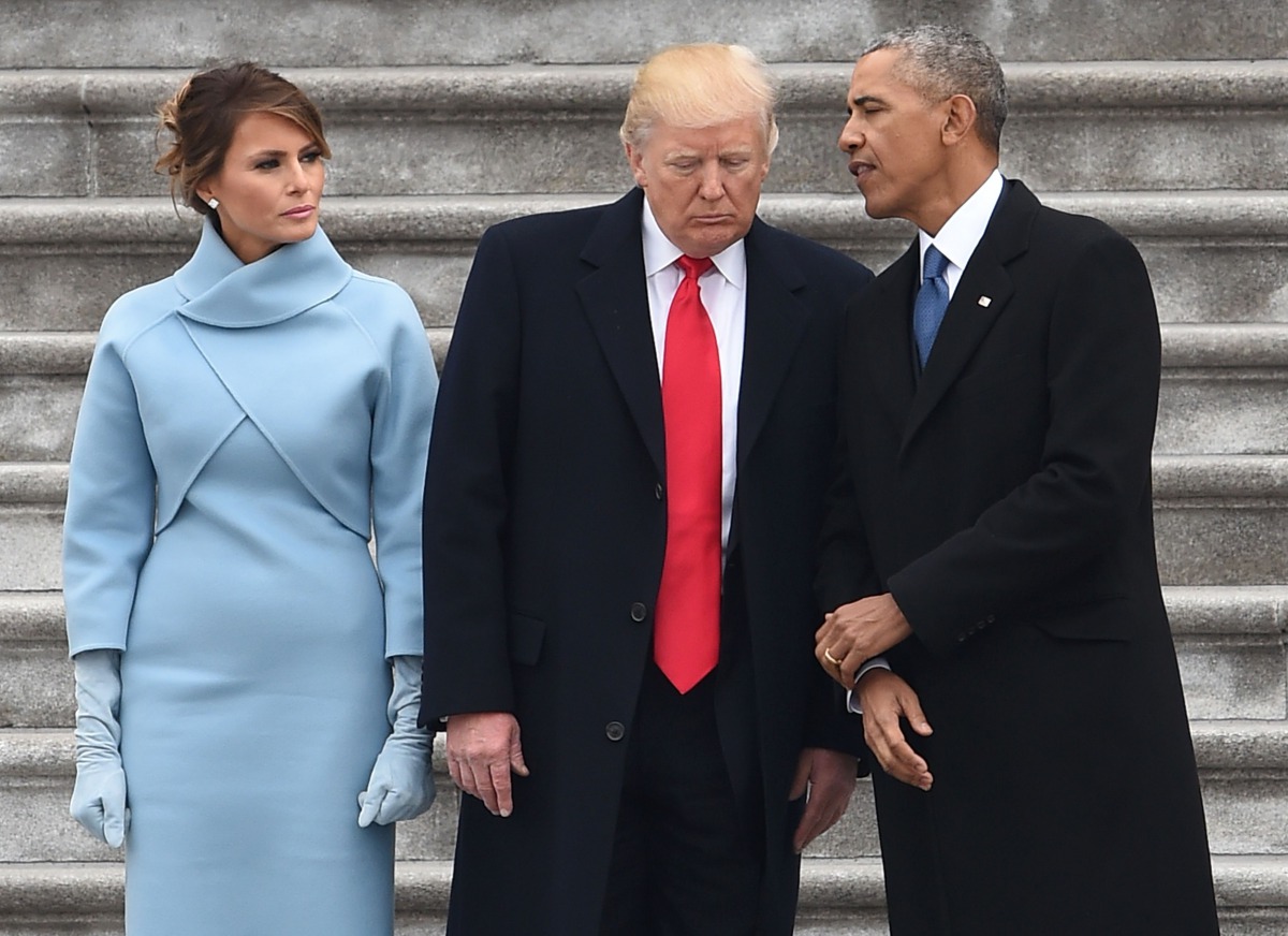 US President Donald Trump speaks to former President Barack Obama as First Lady Melania Trump looks on after inauguration ceremonies at the US Capitol on January 20, 2017 in Washington, DC. / AFP / Robyn BECK