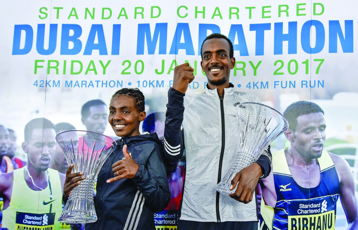 Ethiopian runners Worknesh Degefa (left) and Tamirat Tola celebrate on the podium after winning the Dubai marathon yesterday. 