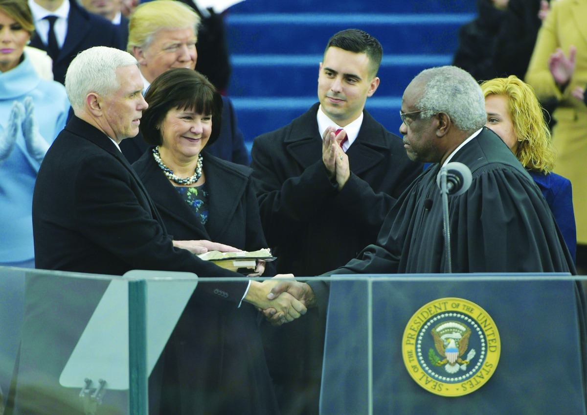 Vice-President Mike Pence shakes hands with justice Clarence Thomas as he takes the oath of allegiance during his swearing-in. His wife Karen Pence and others look on.