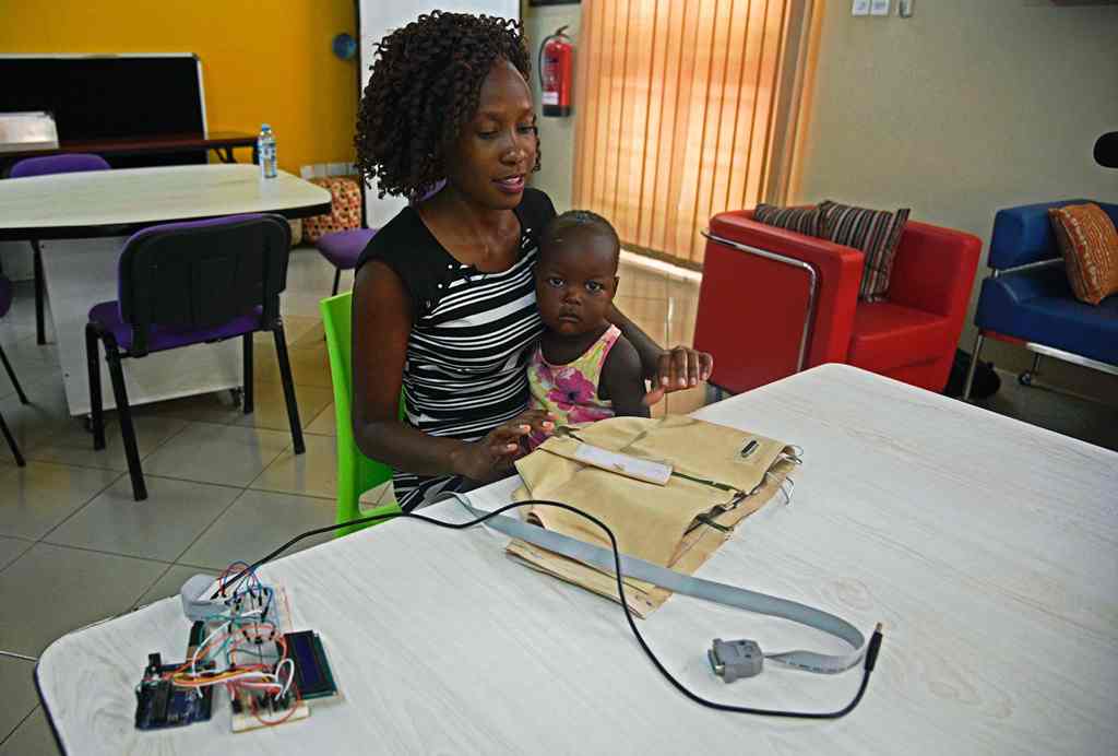 Telecommunications engineer Olivia Koburongo holds a baby in front of pneumonia-diagnosing 