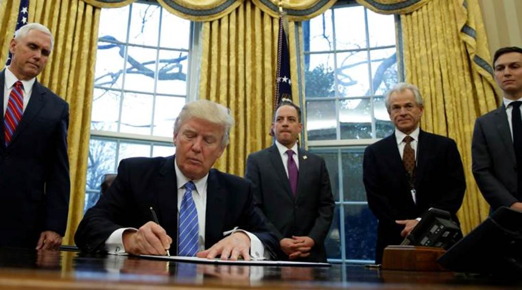US President Donald Trump, watched by (L-R) Vice President Mike Pence, White House Chief of Staff Reince Priebus, head of the White House Trade Council Peter Navarro and senior advisor Jared Kushner, in the Oval Office of the White House in Washington Jan