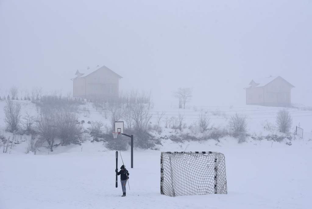 A child walks on a football field covered with snow near the village of Kllokot on January 24, 2017, as the country continues to experience subzero temperatures. / AFP / Armend NIMANI