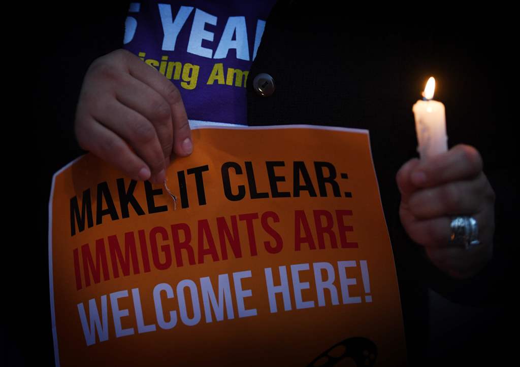 Migrant rights groups hold candles during a vigil to protest against US President Donald Trump's new crackdown on 