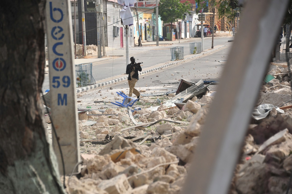 A Somalian policeman holds a weapon following an attack outside an hotel on January 25, 2017, in Mogadishu. Many people were killed after two car bombs exploded outside a popular Mogadishu hotel and gunmen forced their way inside the building and opened f