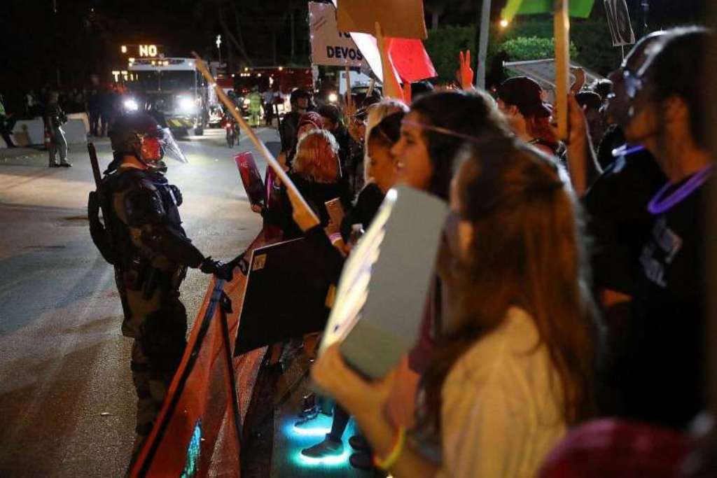 Palm Beach County Sheriff officers with some in riot gear keep protesters against President Donald Trump back from the entrance to Mar-a-Lago Resort where the president is staying for the weekend.PHOTO: AFP.