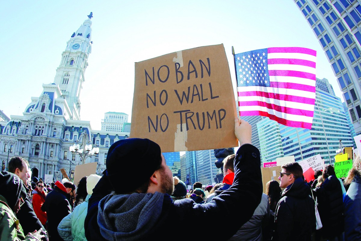 Protester Brandon McTear holds a sign and the American Flag as demonstrators gather to protest against US President Donald Trump, during a rally in Philadelphia, Pennsylvania.