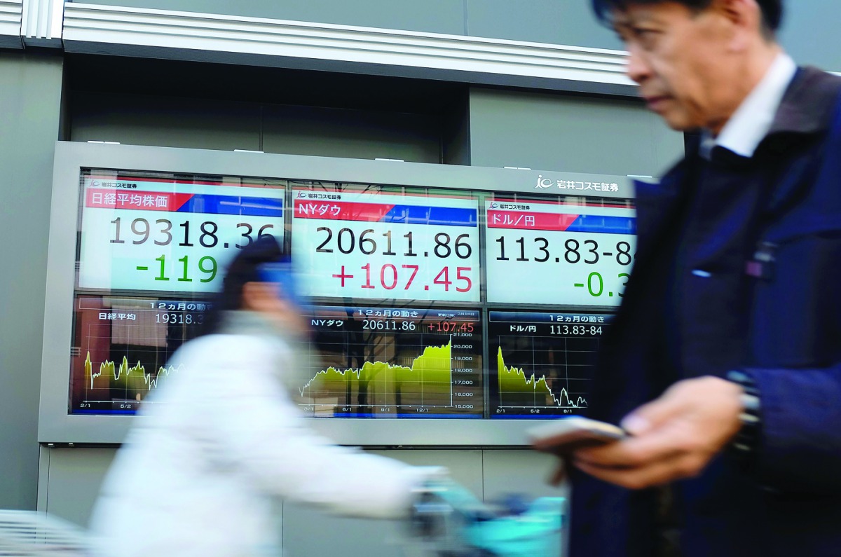 Pedestrians pass in front of electric quotation boards flashing the Nikkei index of the Tokyo Stock Exchange and the current exchange rate of the yen against dollar in Tokyo.