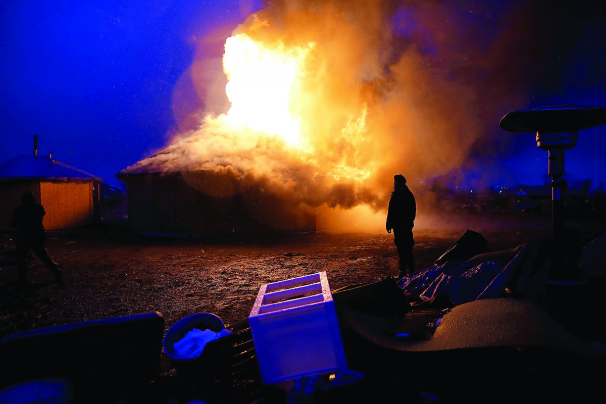 A man watches a building burn after it was set alight by protesters preparing to evacuate the main opposition camp against the Dakota Access oil pipeline near Cannon Ball, North Dakota, US, yesterday.