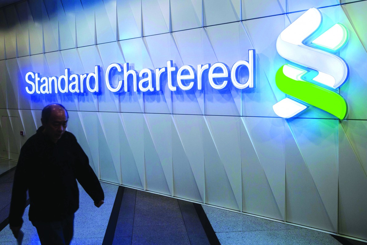 A pedestrian walks past a Standard Chartered sign in the Central district of Hong Kong.