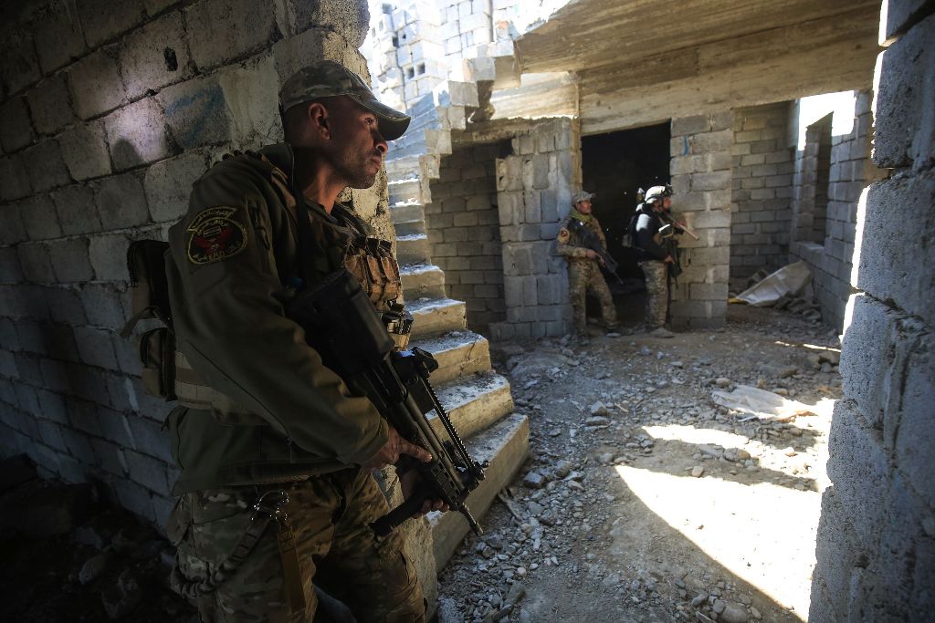 Members of the Iraqi forces take cover as they advance towards Dindan neighborhood in the western half of the northern city of Mosul, as part of the offensive to retake the area from Islamic State (IS) group fighters, on February 25, 2017. AFP / AHMAD AL-